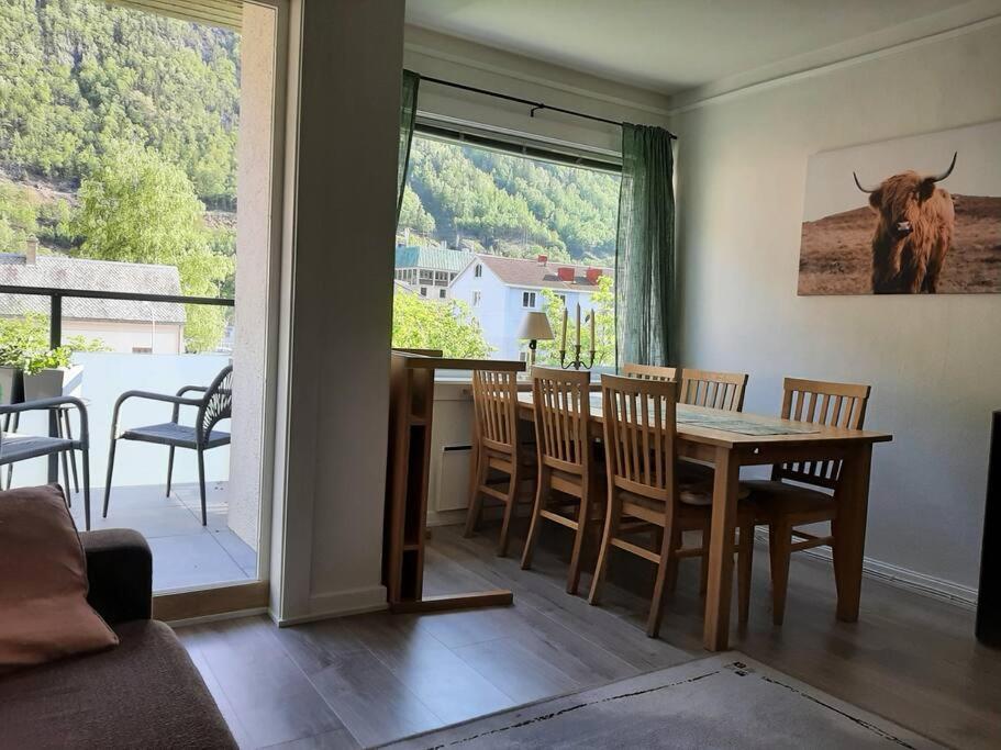 Apartment in Rjukan في Rjukan: غرفة طعام مع طاولة وكراسي وبقرة على النافذة