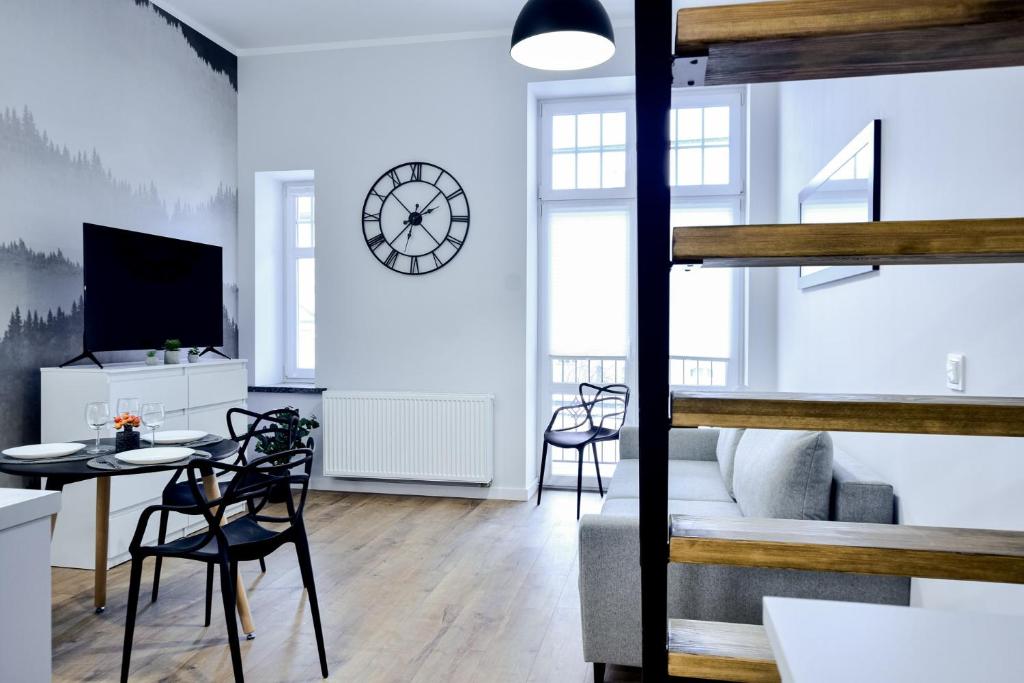 a living room with a table and chairs and a clock at VacationClub - Old Town Apartament 2 in Kłodzko