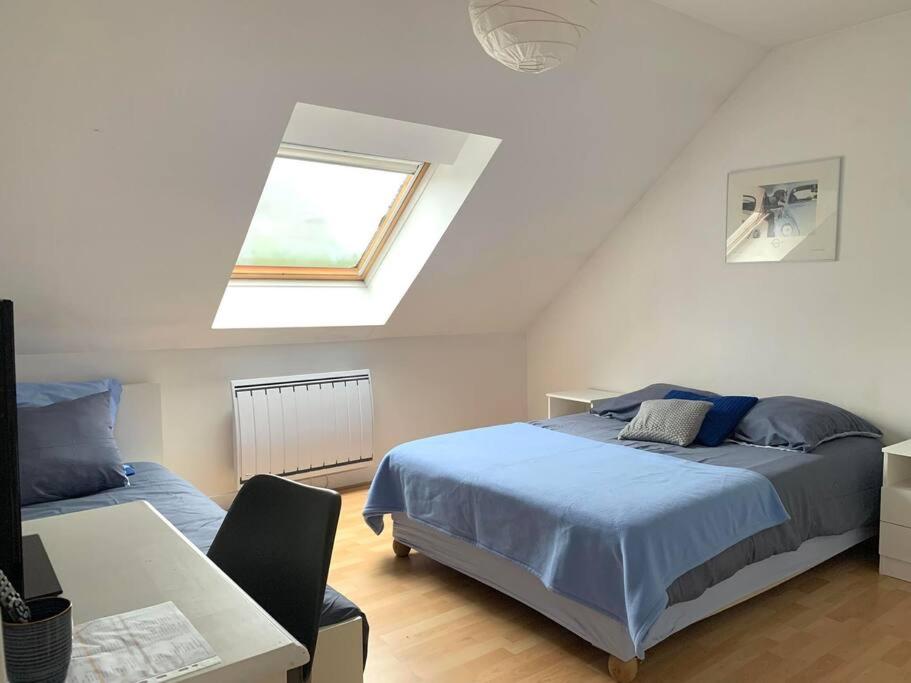 een slaapkamer met een blauw bed en een raam bij Maison Familiale proche de Paris in Montesson