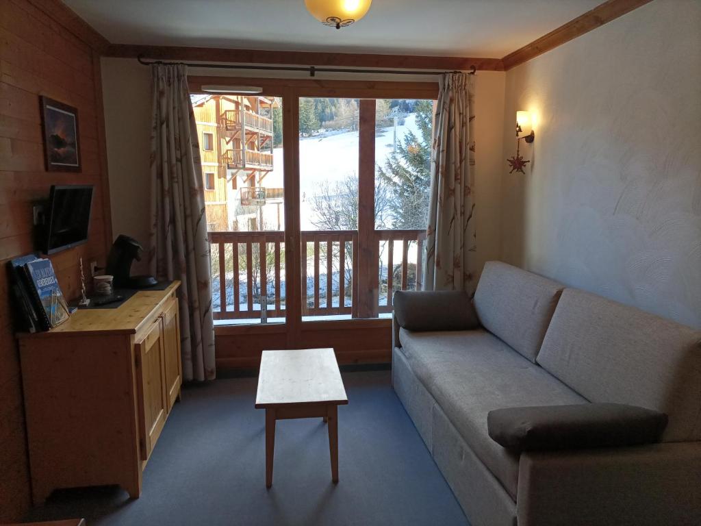 a living room with a couch and a large window at Résidence Les Alpages 4 étoiles - Appartement 4 personnes - Piscine, Hammam, Sauna, Jacuzzi - ValCenis 73480 in Lanslebourg-Mont-Cenis