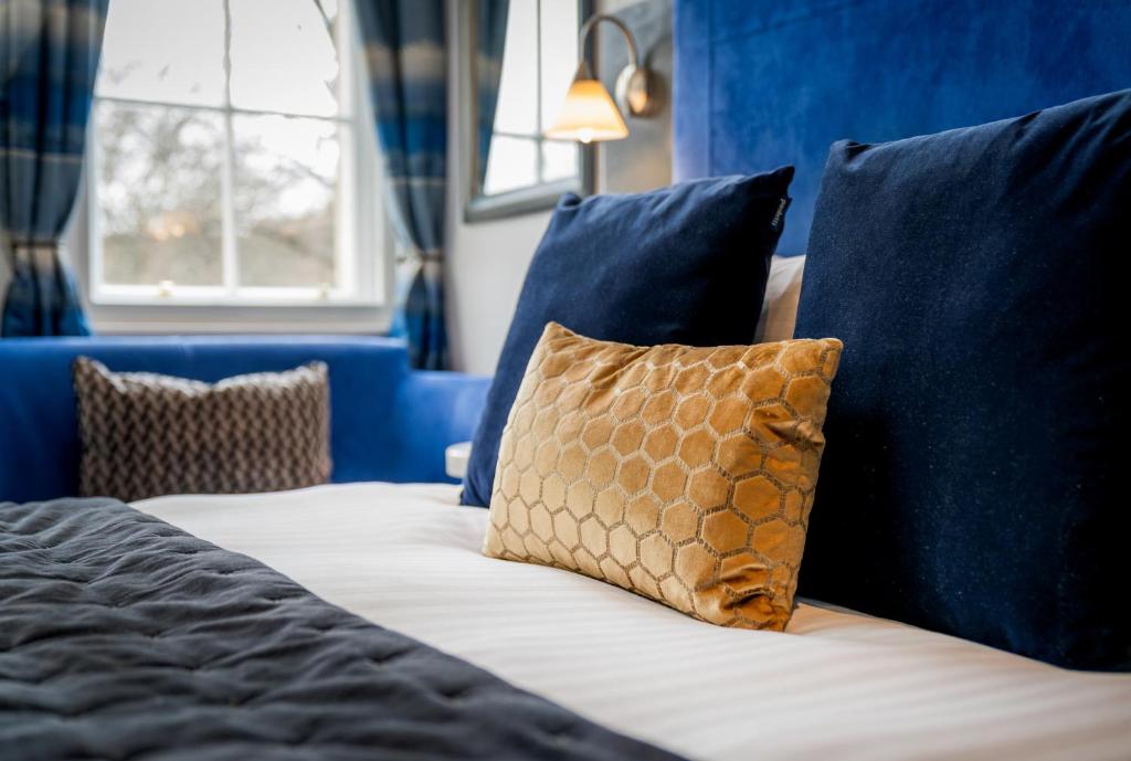 Una cama con almohadas azules y una almohada marrón. en The Berkeley Square Hotel Bristol en Bristol