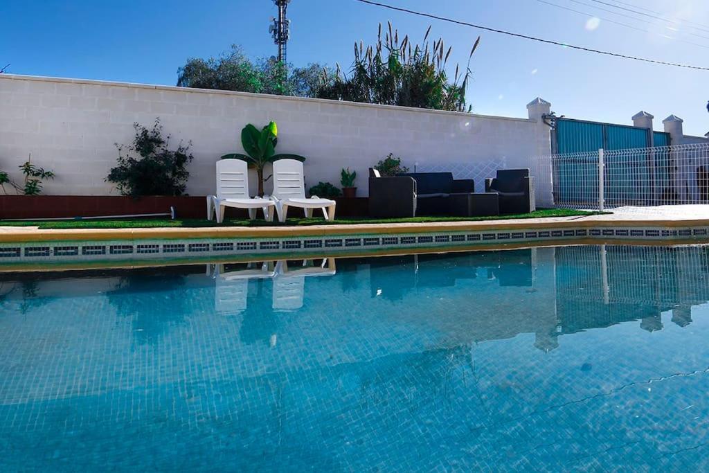 a swimming pool with two chairs and a couch at Villa Parra in Chiclana de la Frontera