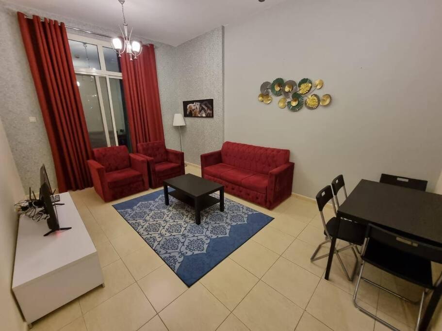 a living room with a red couch and a table at Wonderful 1bhk at silicon oasis in Dubai
