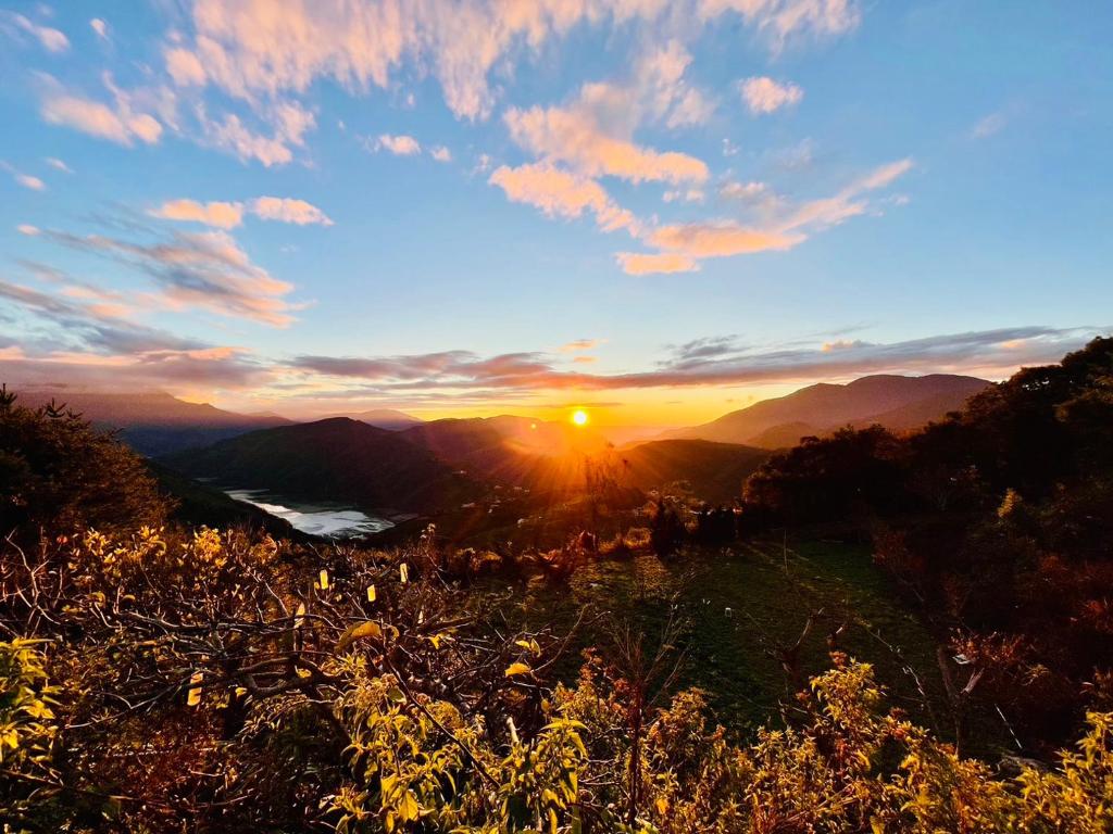 a sunset in the mountains with the sun setting at Junyi Landscape Villa in Ren&#39;ai