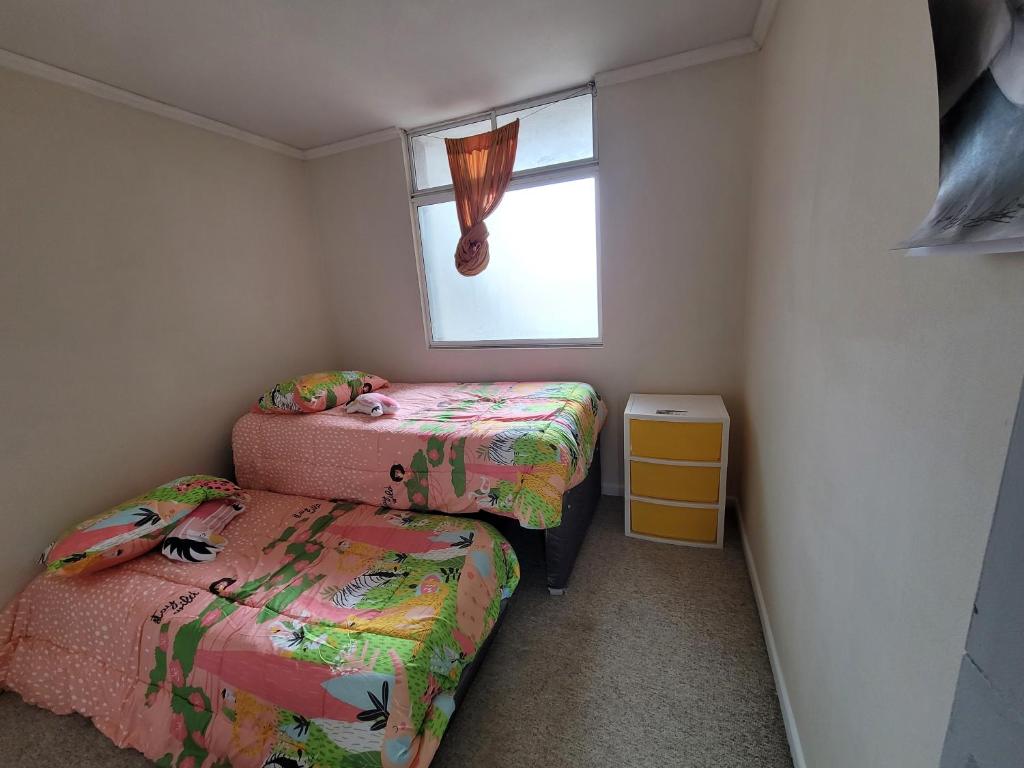 a small bedroom with two beds and a window at Depto. Frente a playa y supermercado in Coquimbo