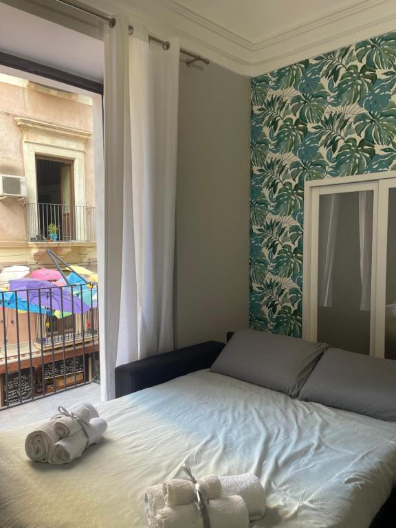 een slaapkamer met een bed met twee handdoeken erop bij Riccioli Home in Catania