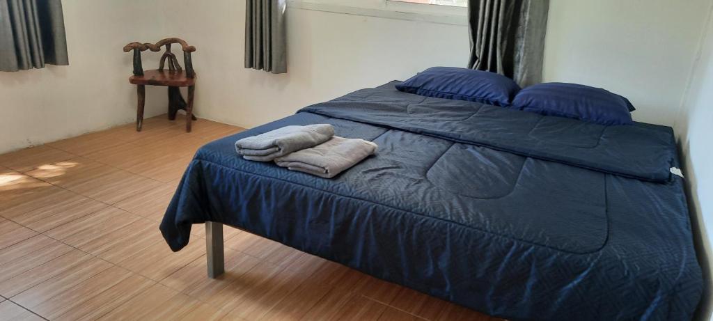 ein Bett mit blauer Bettwäsche und zwei Handtüchern darauf in der Unterkunft โฮมสเตย์แม่ปราณี4 