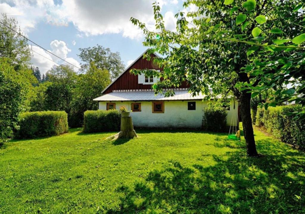 una casa blanca con techo rojo en un patio en Chaloupka Malá Morávka, en Malá Morávka