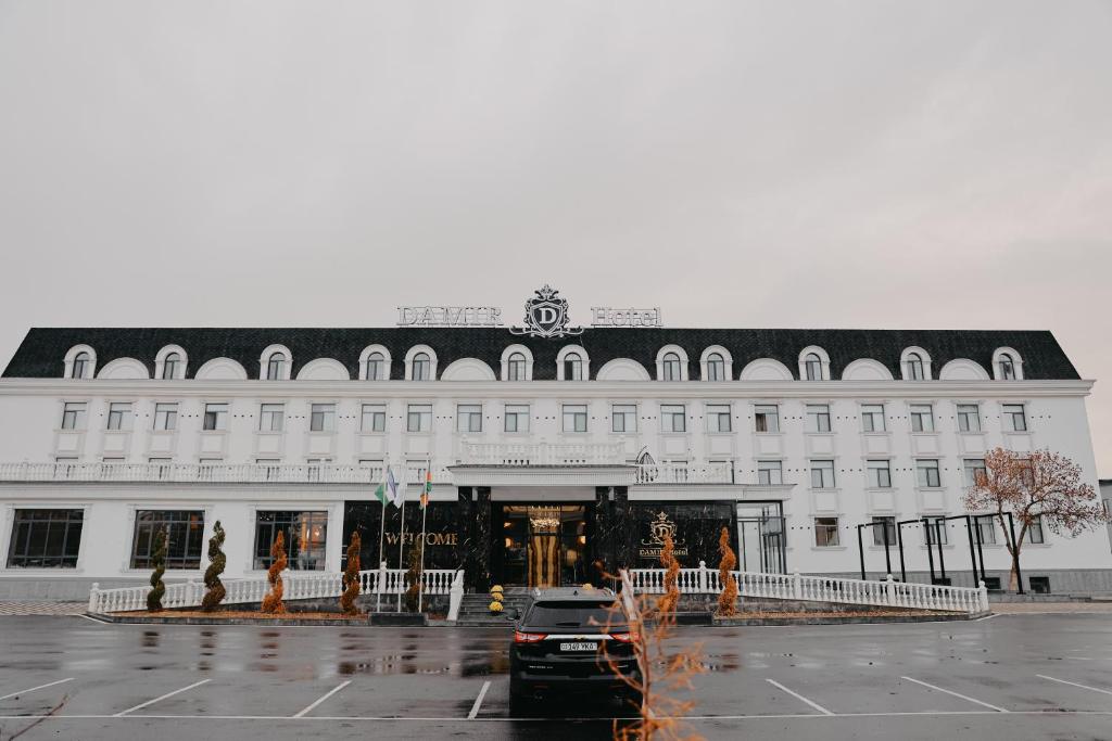 a large white building with a black roof at DAMIR HOTEL in Nukus