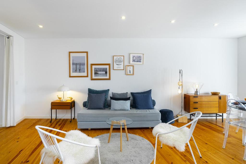 ein Wohnzimmer mit einem blauen Sofa und Stühlen in der Unterkunft Lisbon's Horizon Retreat: A View to Remember in Lissabon