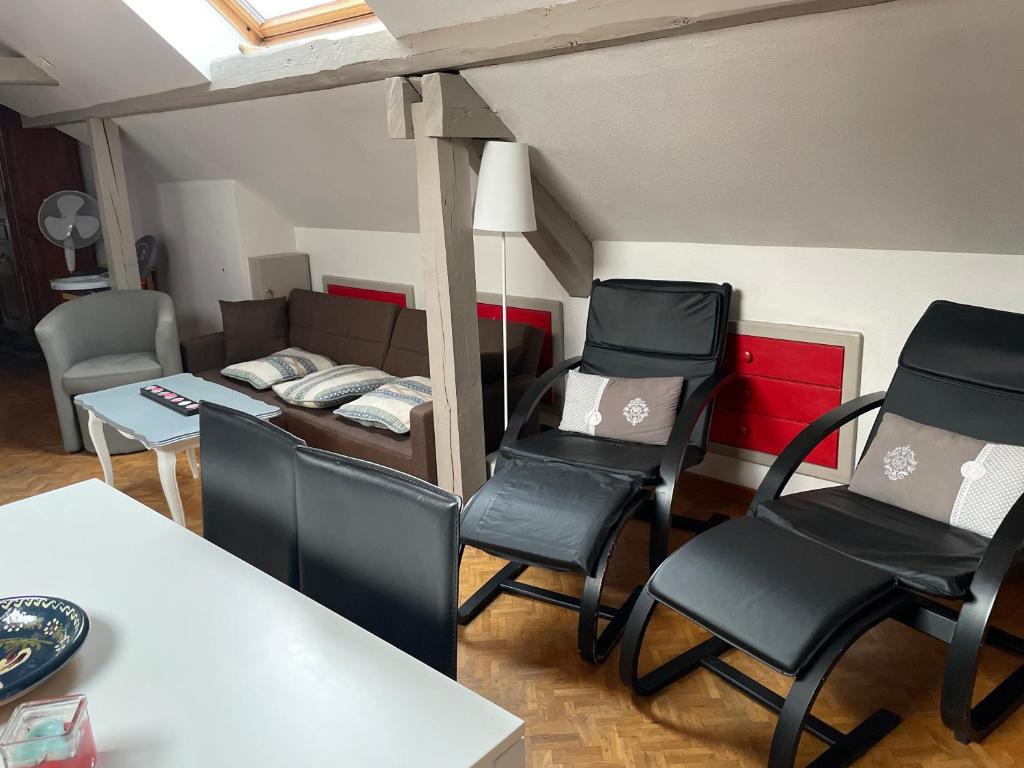 ein Wohnzimmer mit schwarzen Stühlen und einem Sofa in der Unterkunft "Côté cœur", charmant appartement au centre de Munster in Munster