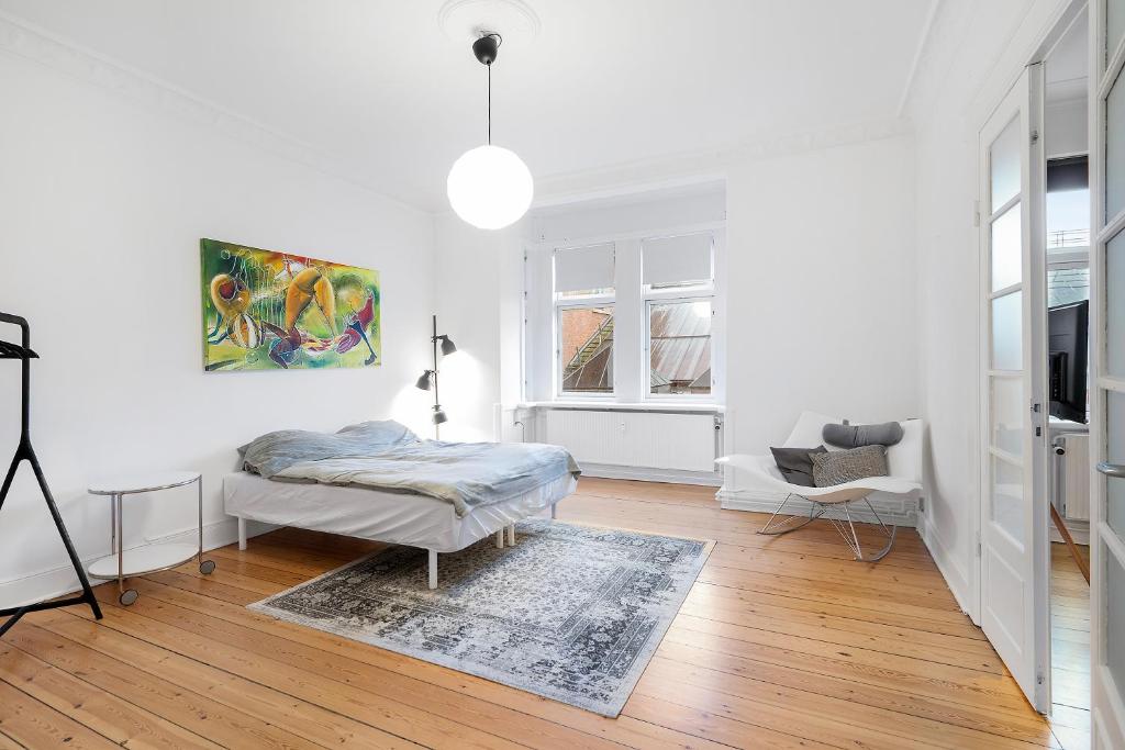 a white room with a bed and a chair in it at Come Stay - With Family or Friends in the heart of Aarhus in Aarhus