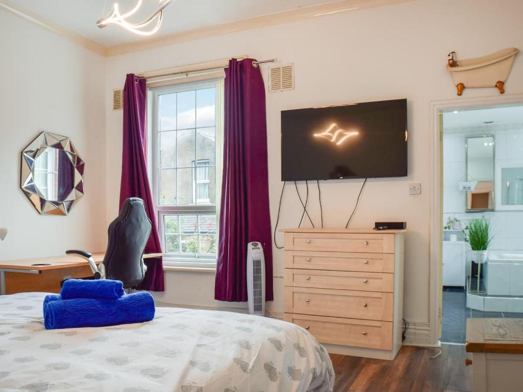 Cette chambre comprend un lit avec des rideaux violets et une télévision. dans l'établissement Valencia, à Blackpool