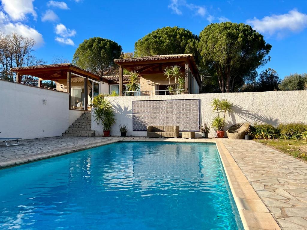 a swimming pool in front of a house at Au Bonheur Dezange in Pézenas