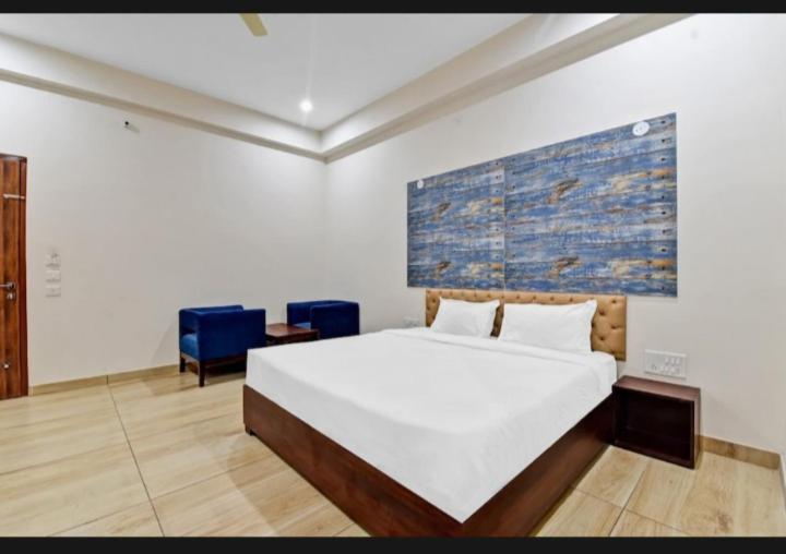 una camera da letto con un grande letto bianco e sedie blu di Hotel Amrapali Inn Jaipur a Jaipur