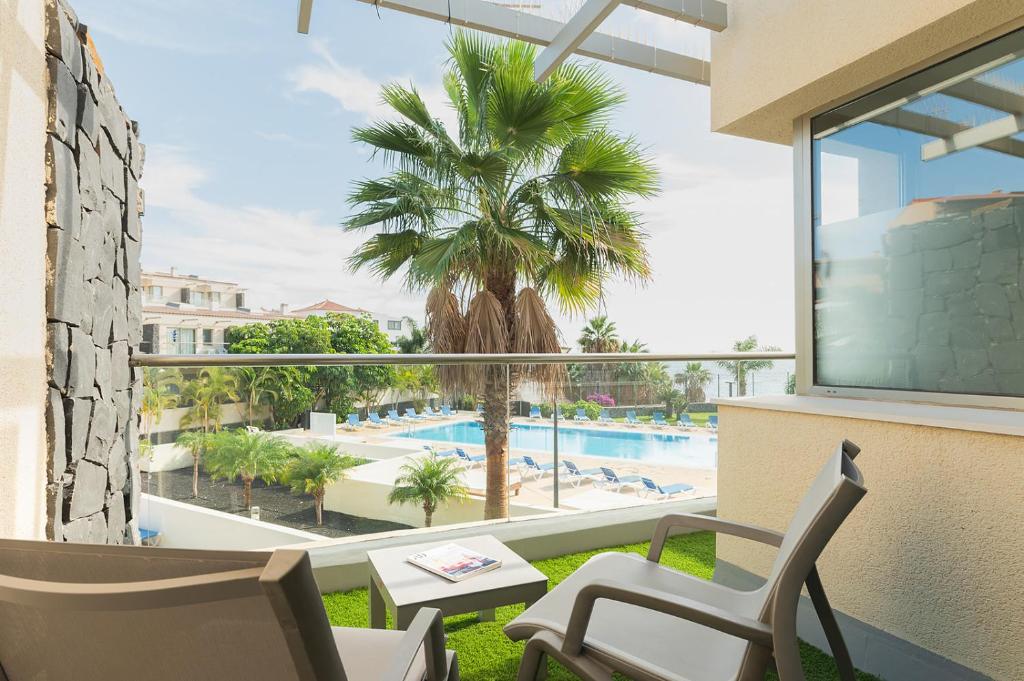 a balcony with a view of a palm tree and a pool at Relax Golf cerca de la playa in San Miguel de Abona