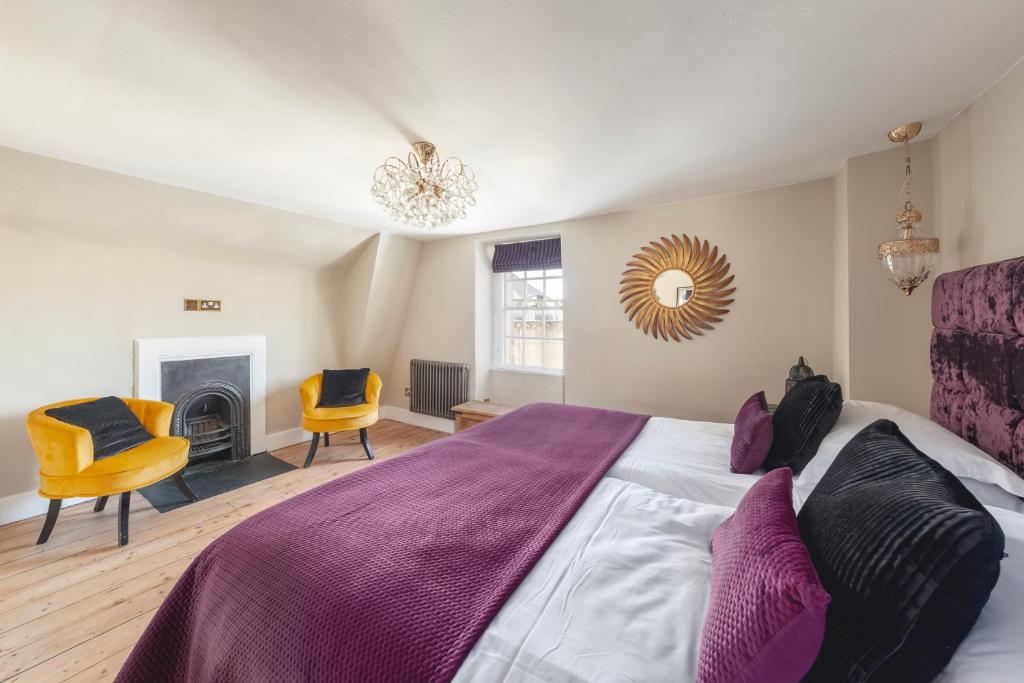 a bedroom with a bed and two chairs and a fireplace at Darcys' Pride in Bath