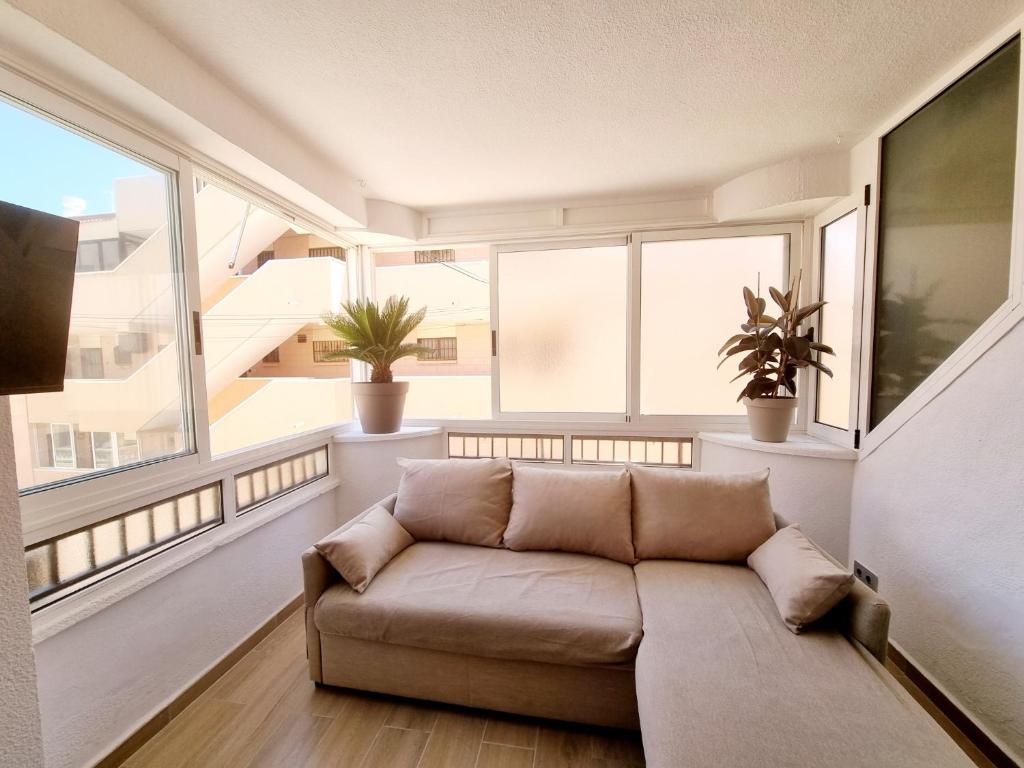 a living room with a couch in front of windows at Elizabeta - Playa Mil Palmeras in Campoamor