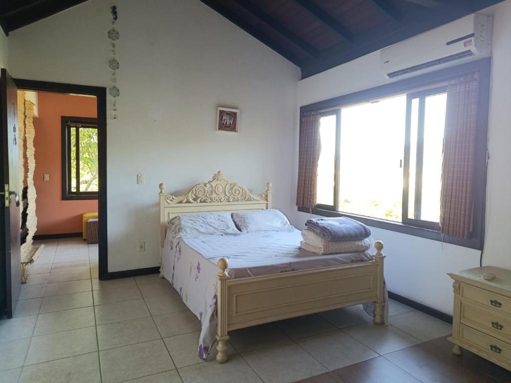 - une chambre avec un lit dans une pièce dotée de fenêtres dans l'établissement Casa Vôo do Beija Flor, à Porto Belo