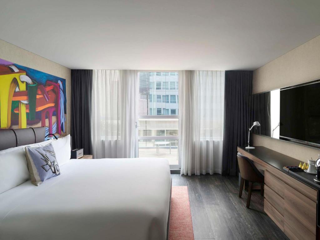 ein Hotelzimmer mit einem großen Bett und einem TV in der Unterkunft Mondrian Mexico City Condesa in Mexiko-Stadt