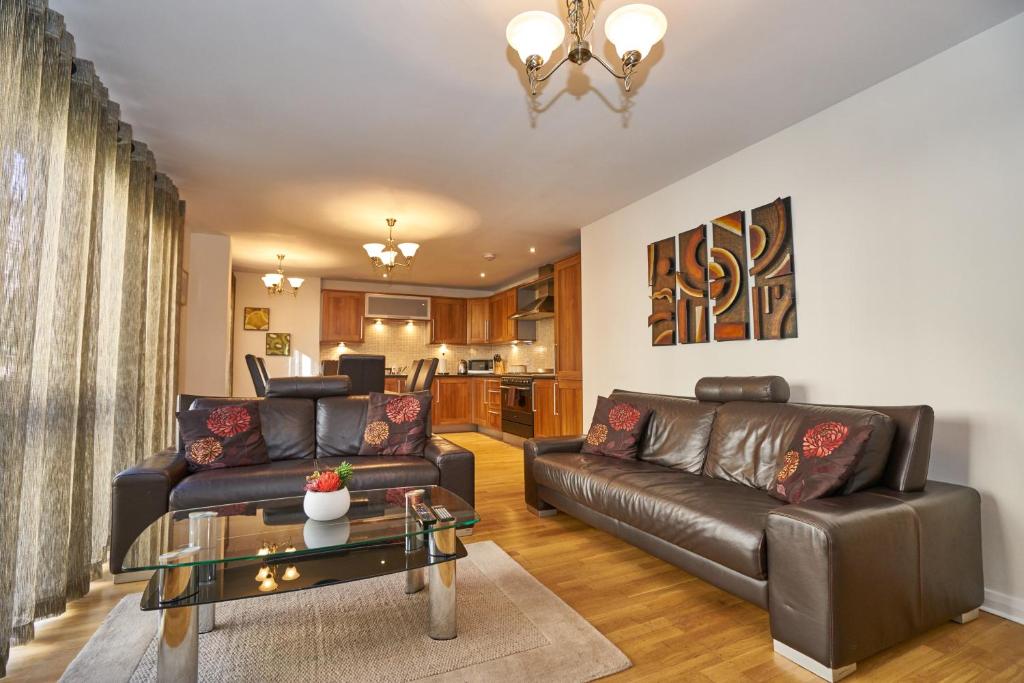 ein Wohnzimmer mit einem Ledersofa und einem Tisch in der Unterkunft Fountainbridge Residence in Edinburgh
