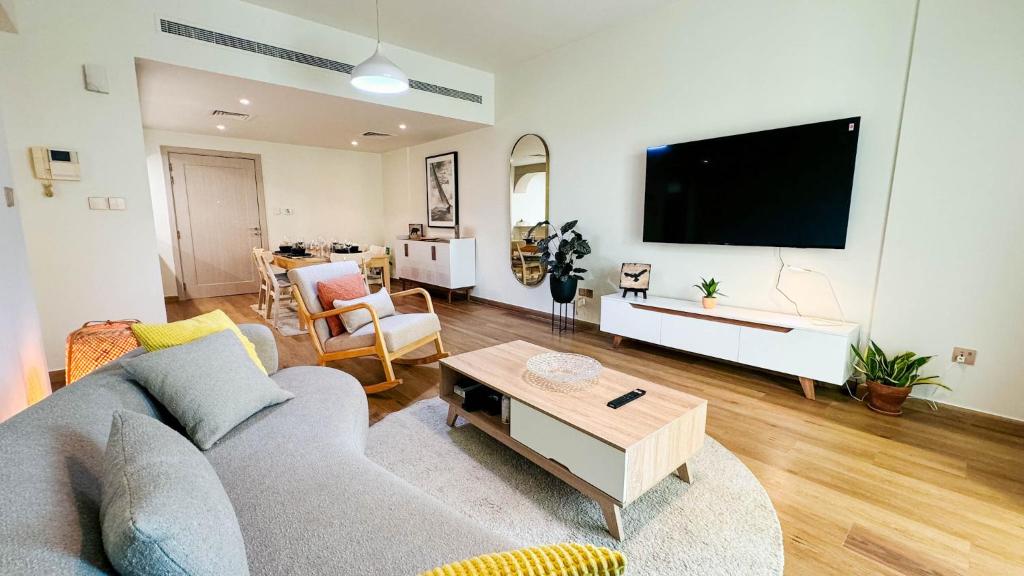 a living room with a couch and a flat screen tv at Tranquil 1BR Garden Retreat Dubai Greens in Dubai