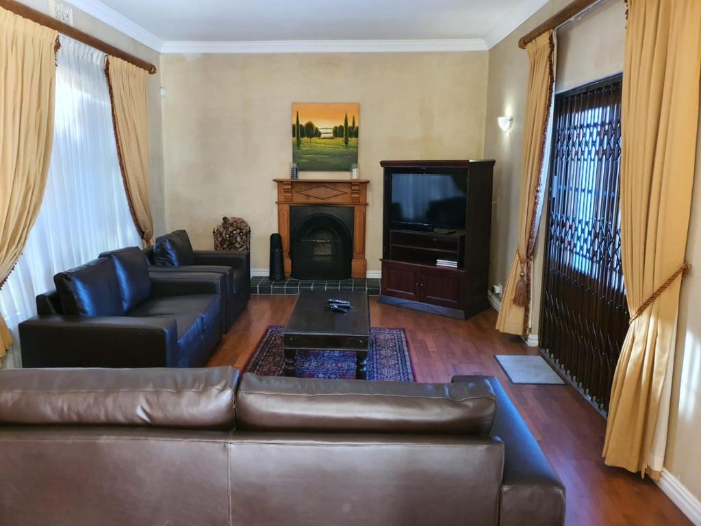 a living room with a leather couch and a television at Ringwood Villa in Cape Town