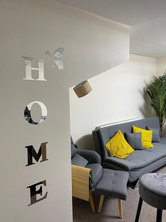 sala de estar con sofá azul y almohadas amarillas en GM247 Nice Accommodation Stays, en Wigan