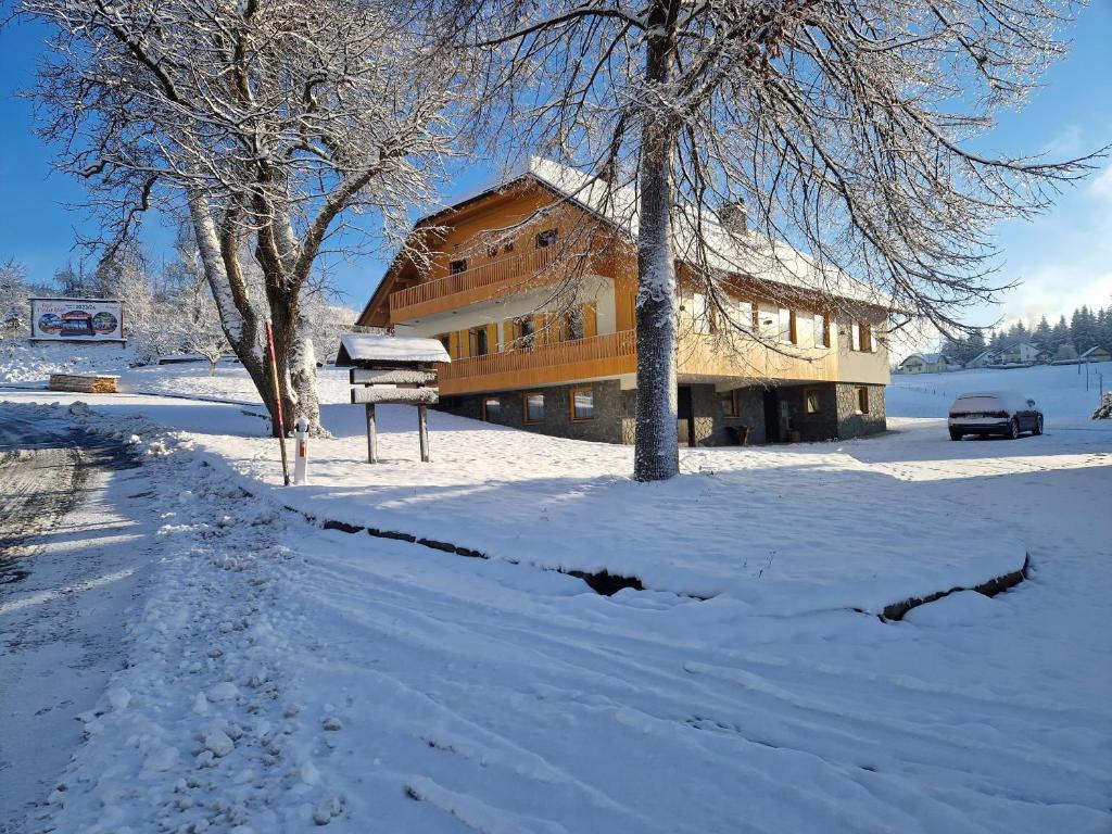 ein Gebäude im Schnee mit einem Auto vor der Tür in der Unterkunft Farm Stay Ramšak in Zreče