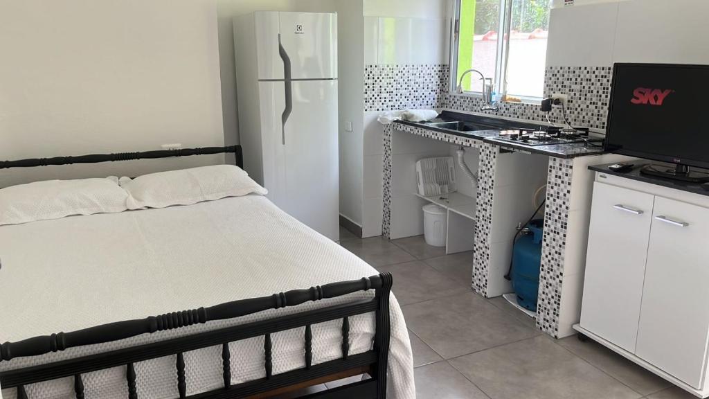 a small bedroom with a bed and a refrigerator at Chalé Orquidea in São Sebastião