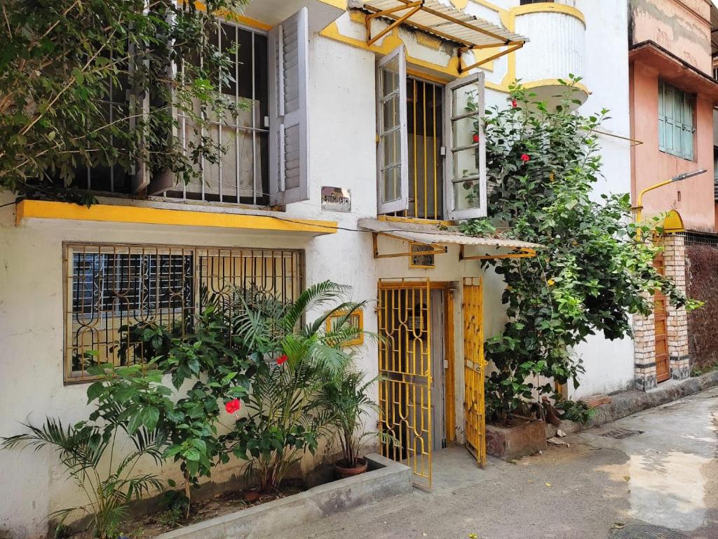 a building with yellow doors and plants on a street at Happy Home in Kolkata