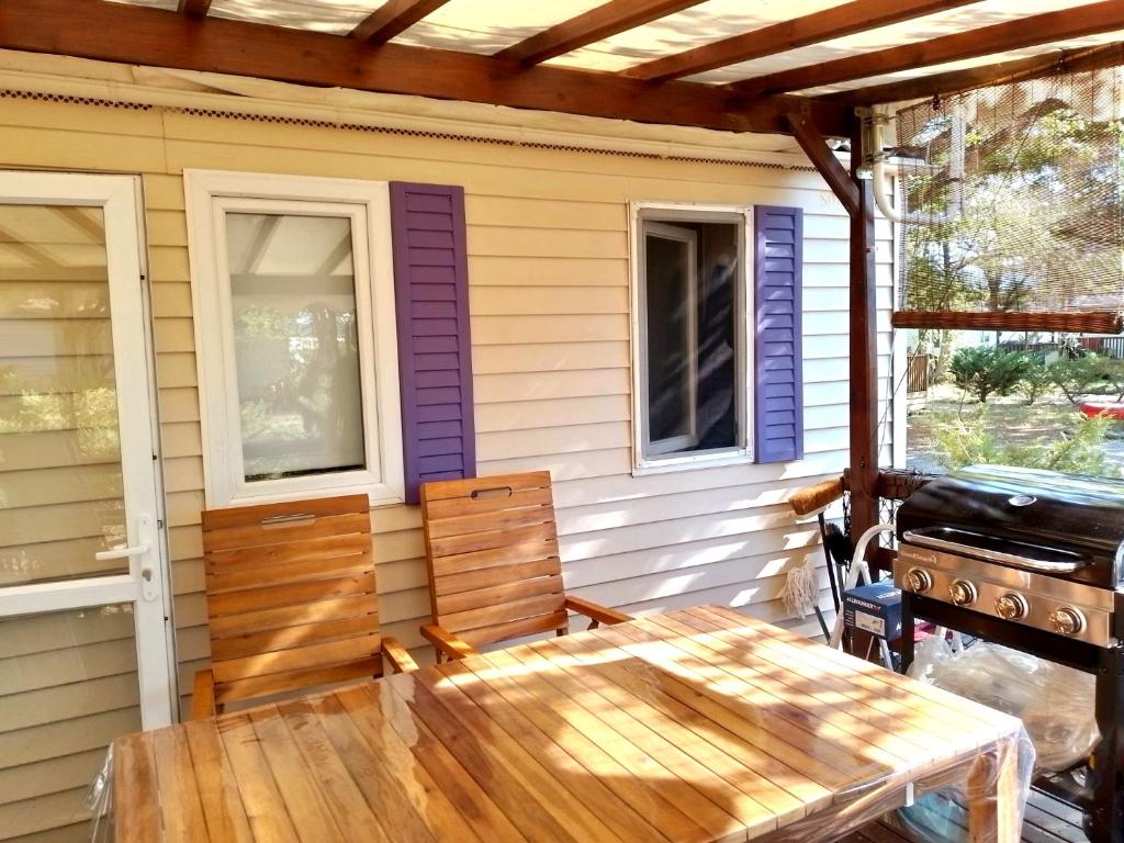 a porch with a wooden table and a grill at Camping, mobil home équipé proche du lac de Sainte Croix et des gorges du Verdon in Sainte-Croix-de-Verdon