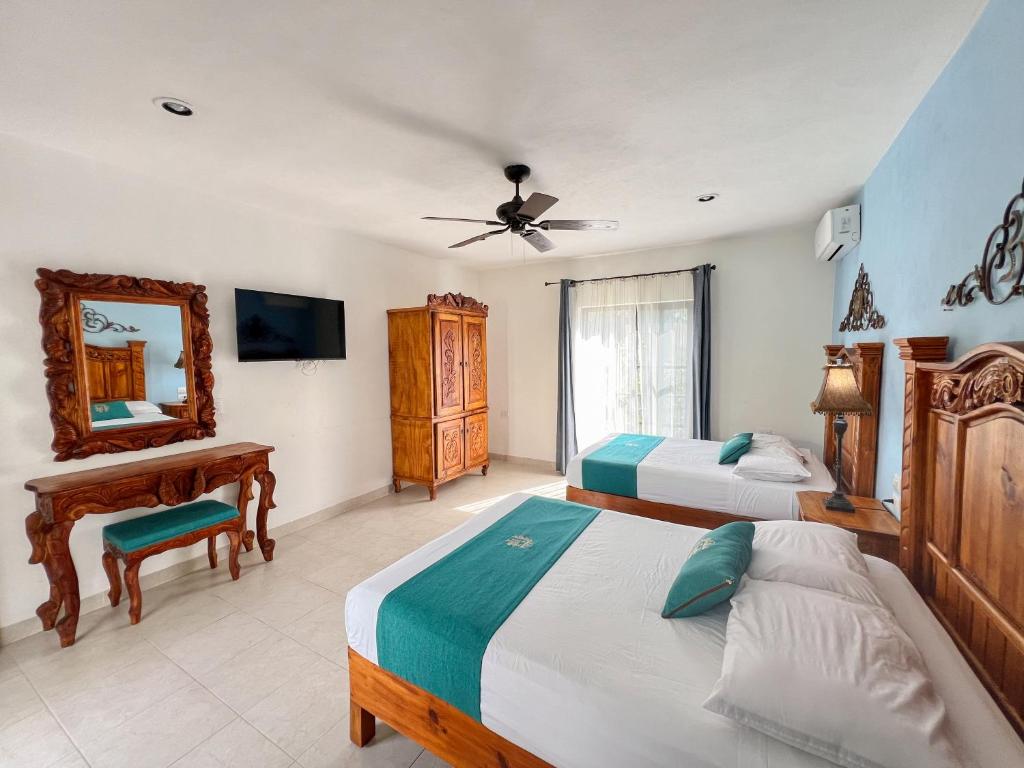 a bedroom with two beds and a desk and a mirror at Hotel Fundadores in Valladolid