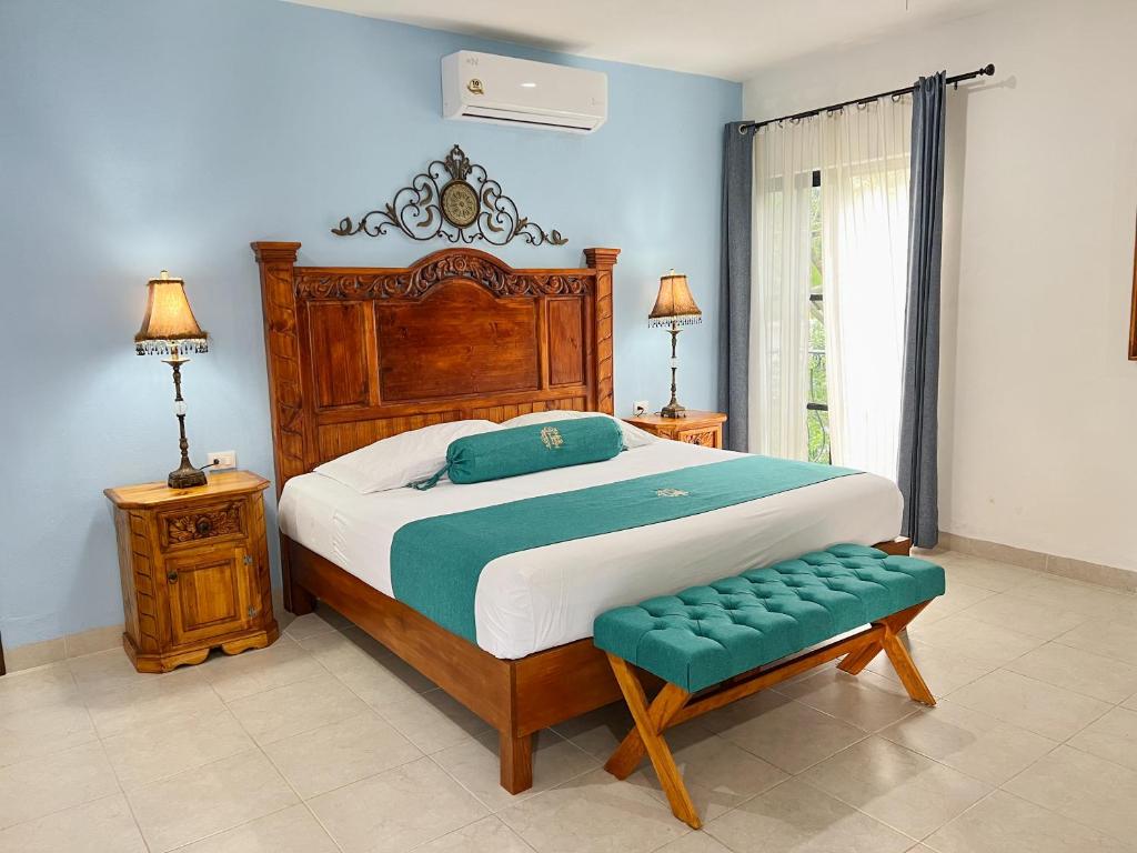a bedroom with a large bed and a green bench at Hotel Fundadores in Valladolid