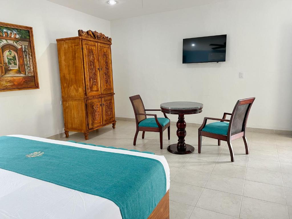 a bedroom with a bed and chairs and a table at Hotel Fundadores in Valladolid