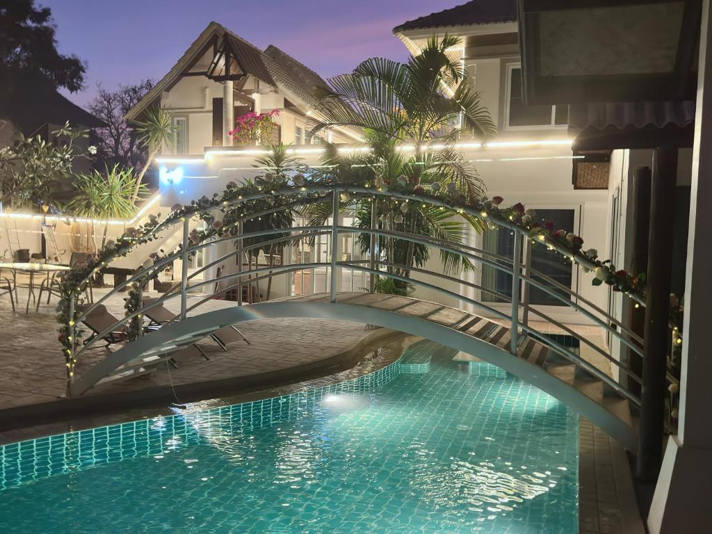 a bridge over a swimming pool in front of a house at Pheonix Golf Pool Resort Villa in Ban Huai Yai