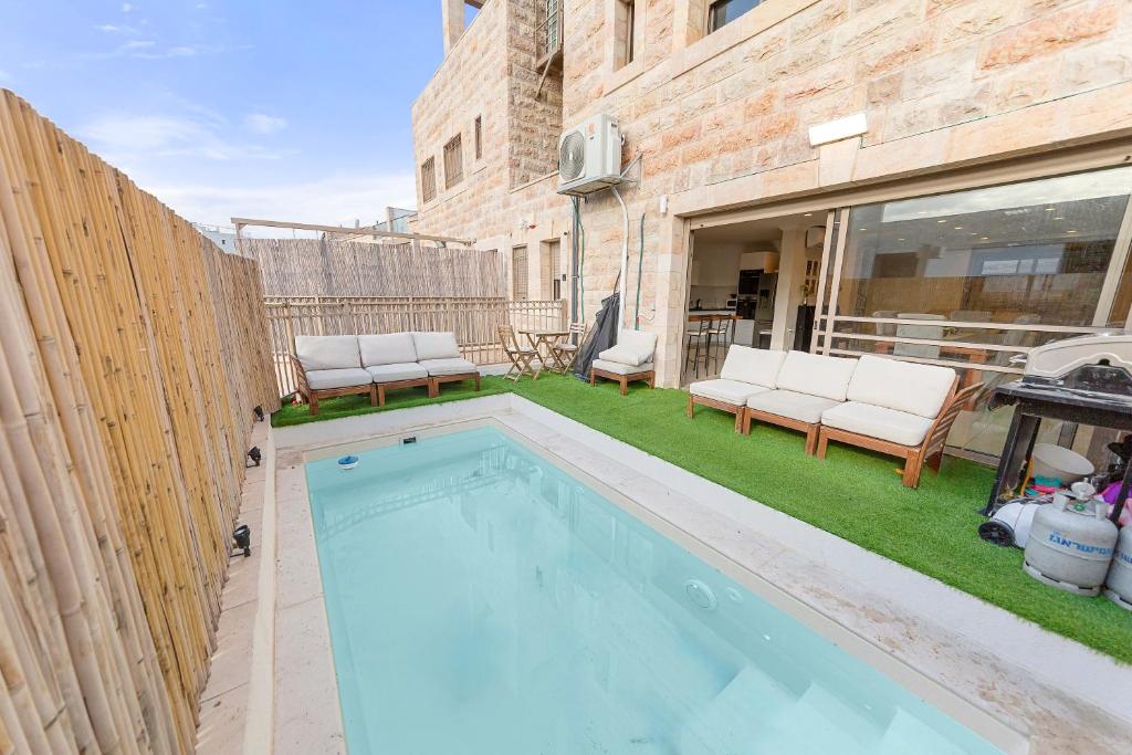einen Pool mit zwei Stühlen und einem Zaun in der Unterkunft Chateau Gabriel Luxury 6 BR Villa with Heated Pool in Bet Schemesch