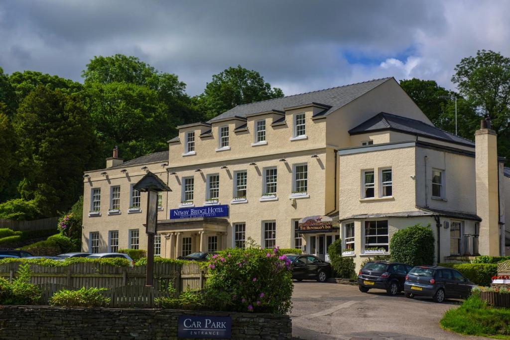 a large white building with cars parked in a parking lot at Newby Bridge Hotel in Newby Bridge