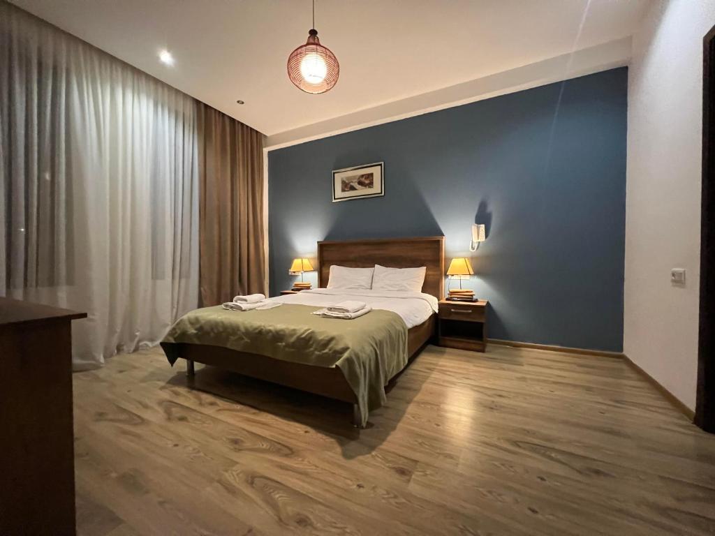 a bedroom with a bed and a blue wall at Hotel King Tom in Tbilisi City