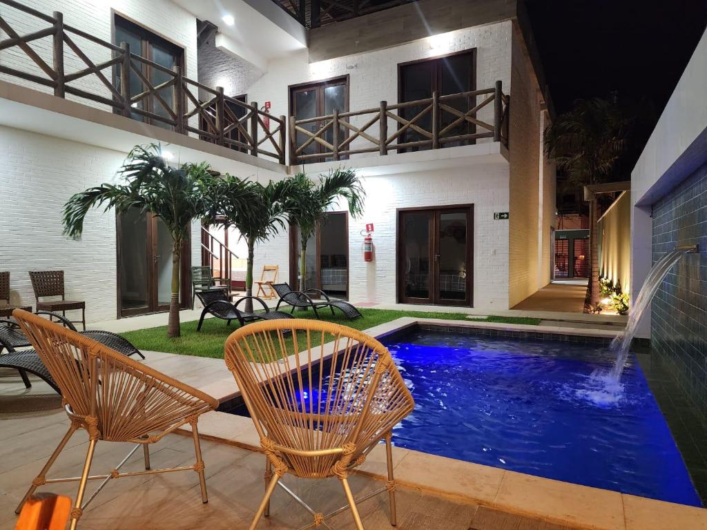 ein Haus mit einem Pool und zwei Stühlen in der Unterkunft Pousada Solarium in Canoa Quebrada