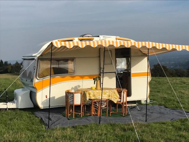 a camper with a table and chairs in a field at The Mighty Atom - 1976 2 berth Safari Retro Caravan in Abergavenny