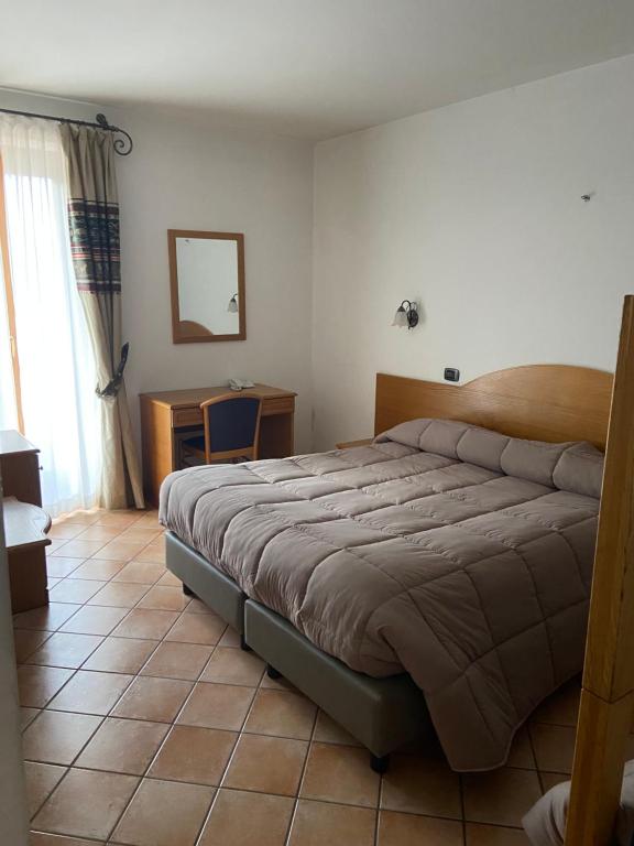a bedroom with a bed and a table and a mirror at HOTEL MILLE PINI in Ovindoli