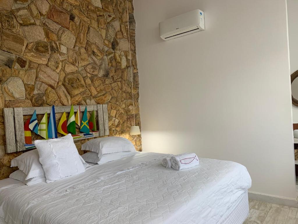 a bedroom with a large bed with a stone wall at Almas Gêmeas suíte com cozinha praia da Ribeira in Angra dos Reis