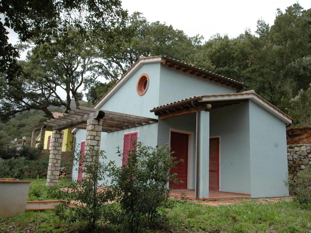 uma pequena casa branca com persianas vermelhas em Villaggio Di Mezzo Ortano em Rio Marina