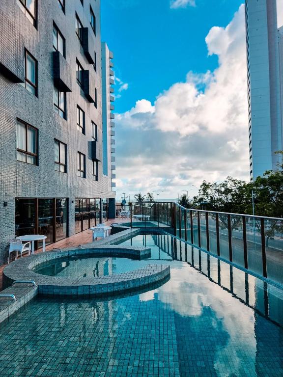 a swimming pool in front of two tall buildings at Ilusion Flat Ponta Negra in Natal