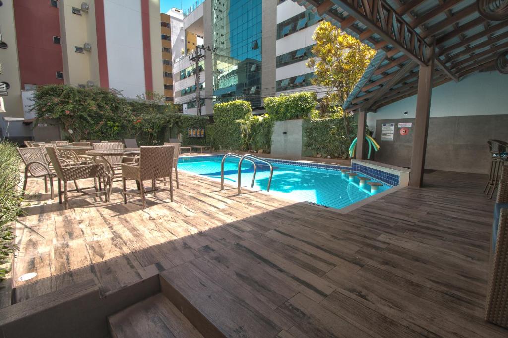 a patio with a table and chairs next to a swimming pool at Hotel Gracher Praia in Balneário Camboriú