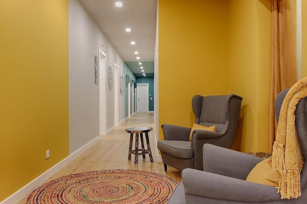 un corridoio con due sedie e un tavolo e pareti gialle di Guesthouse by Trip2Portugal a Lisbona