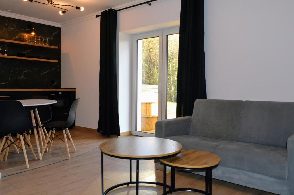 uma sala de estar com um sofá e uma mesa em Leśna Muzyka Apartment Limanowa em Limanowa