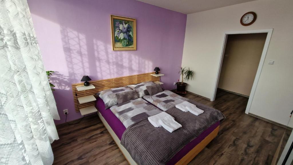 a bedroom with purple walls and a bed with towels at Byt s jedinečným výhledem in Děčín