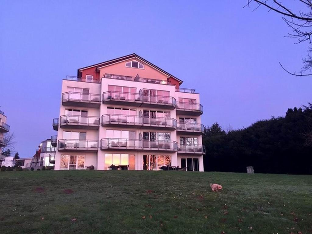 een groot roze gebouw met balkons op een veld bij Apartment zum See in Ascheberg